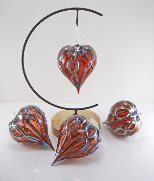Blown glass, heart-shaped ornament with either a pink or red solid colored interior, and a metallic luster on surface. Texture is ribbed with a subtle "hugs-n-kisses" xoxo pattern. Approx. size 3-4" height and width.