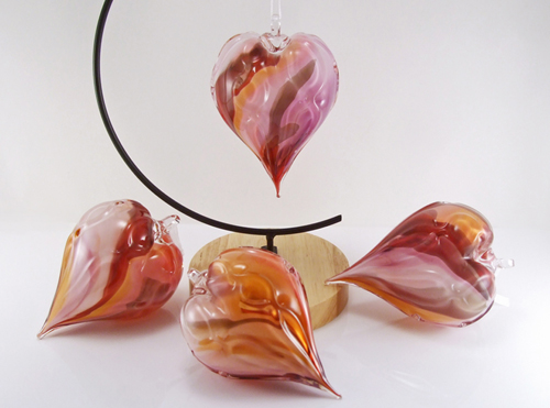 Blown glass, heart-shaped ornament with a combination of colors swirled throughout interior. Surface texture is ribbed with a subtle "hugs-n-kisses" xoxo pattern. Approx size 3-4" height and width