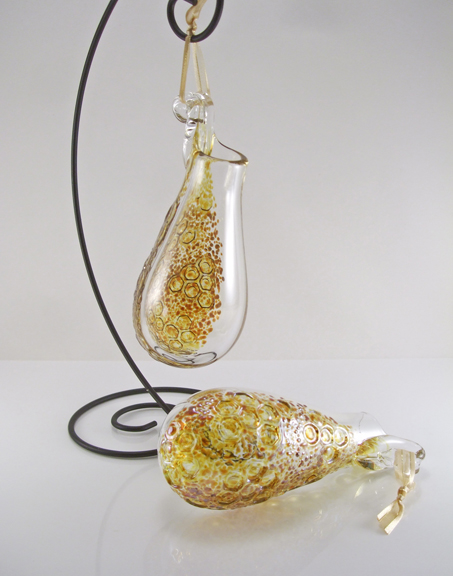 Blown Glass vase, made for suspending from hooks or nails with ribbon. Fill with fresh or dried flowers, root house plants or use as a scented oil diffuser. Backside of glass has iridescent gold color with imprinted honeycomb texture. Approx. 5-7" tall